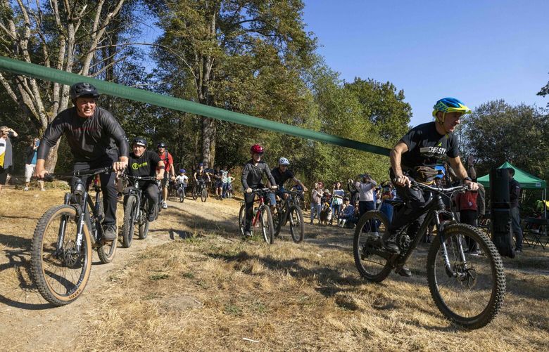 Instead of a ribbon cutting, mountain bike riders to ride under the grand opening banner and ride the trails at the opening of Cheasty Mountain Bike Park on Oct. 1, 2022.