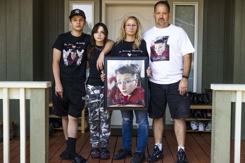 Siblings Ethan, left, and Kacee and parents Amber and David Weilert — the family of Michael Weilert — hold a portrait of him on the porch of their Parkland home in Pierce County.  Michael was killed in a traffic accident last year. (Daniel Kim / The Seattle Times)