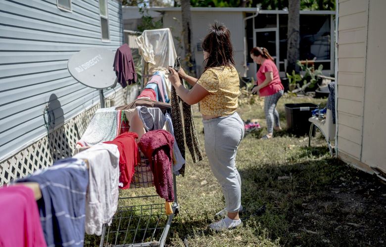 Delmi Murcia, background, and her family dry their belongings in the sun on Saturday, Oct. 1, 2022, after their mobile home flooded in East Naples, Fla. Losses from Hurricane Ian are just coming into focus, but what is clear is that recovery will be hardest on people already struggling to make ends meet. (Emily Kask/The New York Times) XNYT8 XNYT8