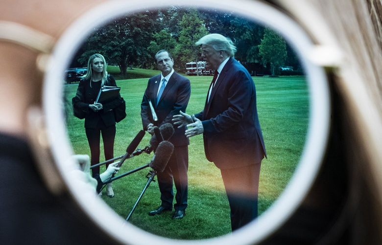 President Donald Trump, Health and Human Services Secretary Alex Azar and White House press secretary Kayleigh McEnany, shown reflected in a pair of sunglasses, speak to reporters on the South Lawn of the White House in May 2020. MUST CREDIT: Washington Post photo by Jabin Botsford