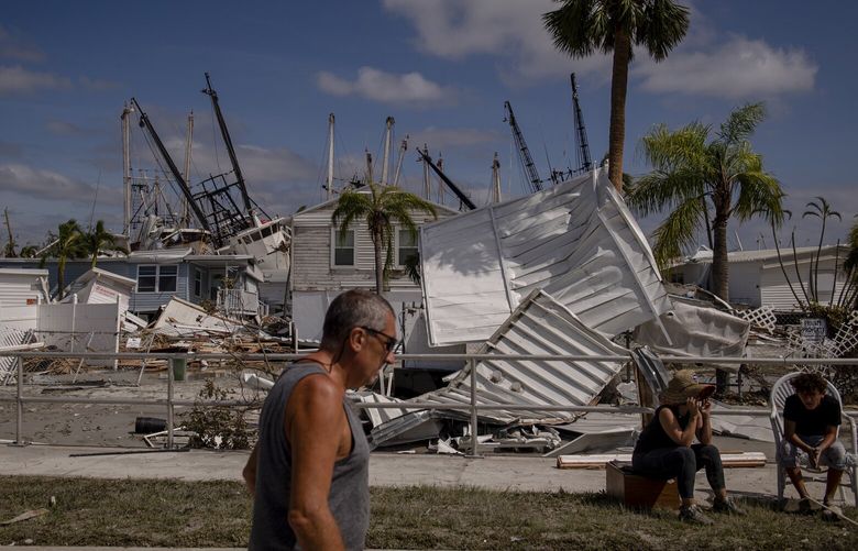 A resident walks in front of the debris that Hurricane Ian left in Fort Myers Beach, Fla., on Sept. 29, 2022. President Biden will receive a briefing on Hurricane Ian from Gov. Ron DeSantis of Florida on Wednesday, Oct. 5, as the president travels to the southwest coast of the state just days after communities there were hammered by the deadly Category 4 storm. (Hilary Swift/The New York Times) XNYT210 XNYT210