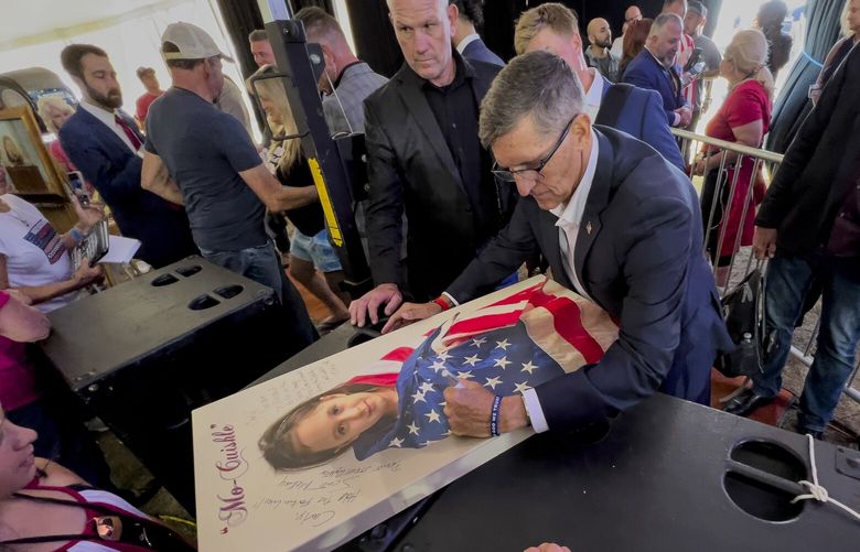 Michael Flynn, a retired three-star general who served as President Donald Trumpâ€™s national security advisor, autographs a picture of a girl wrapped in an American flag during the ReAwaken America Tour at Cornerstone Church in Batavia, N.Y., Friday, Aug. 12, 2022. Flynn, one of the tourâ€™s founders and its star, warned the crowd that they were in the midst of a â€œspiritual warâ€ and urges people to get involved in local politics.” (AP Photo/Carolyn Kaster) XCK312 XCK312