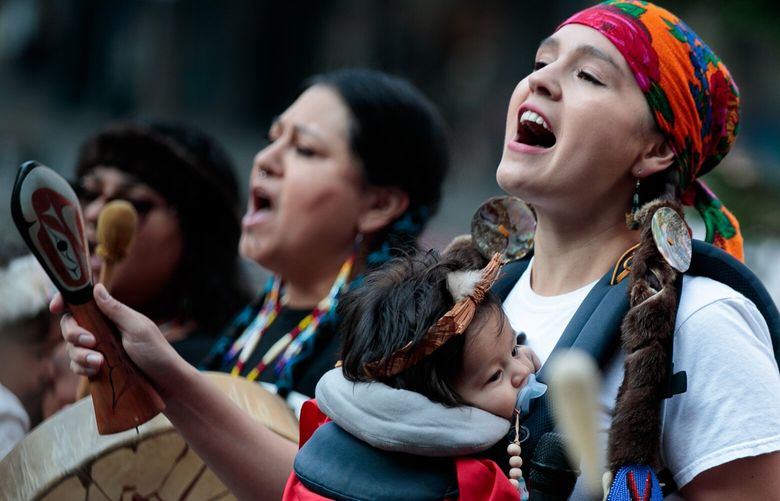 Mariana Harvey, enrolled member of the Confederated Tribes and Bands of the Yakama Nation, sings with Tumna (accent on a), 4 months, before a celebratory march at Westlake Park for Indigenous Peoples’ Day in Seattle Monday, Oct. 10, 2022.