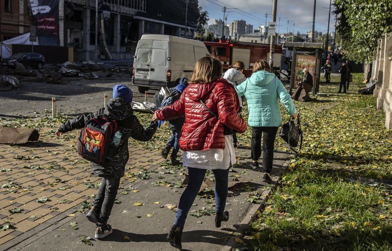 A family runs from the scene of a Russian bombing in Kyiv, Ukraine, on Monday, Oct. 10, 2022. Moscow responded to the assault on the Kerch Strait Bridge with a series of missile attacks across Ukraine. (Finbarr O’Reilly/The New York Times)