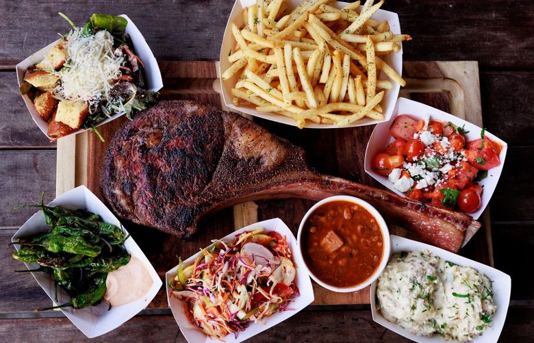 Lady Jaye’s smoked tomahawk ribeye is seen with all of the sides: smoked jalapeno kale caesar, 10 vegetable vinegar slaw, watermelon and tomato salad, shoe string fries, baked odds and ends black eyed peas, Yukon gold horseradish potato salad and fried shishito peppers.