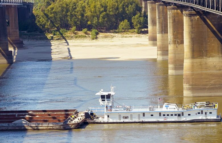 Low-water restrictions on the barge loads make for cautious navigation through the Mississippi River as evidenced by this tow passing between the river bridges in Vicksburg, Tuesday, Oct. 11, 2022. The unusually low water level in the lower Mississippi River has caused some barges and vessels to get stuck in the muddy river bottom, resulting in delays as reported by the U.S. Coast Guard. (AP Photo/Rogelio V. Solis) MSRS107