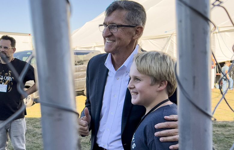 Michael Flynn, a retired three-star general who served as President Donald Trumpâ€™s national security advisor, gives a thumbs-up as he poses for a photograph with a young supporter outside the tent during the ReAwaken America Tour at Cornerstone Church in Batavia, N.Y., Friday, Aug. 12, 2022. (AP Photo/Carolyn Kaster) XCK315 XCK315