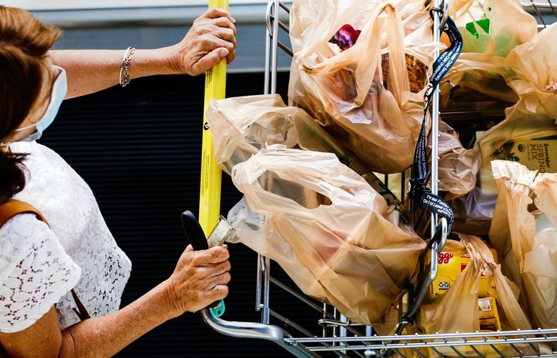 FILE – A woman leaves a supermarket in Miami Beach, Fla., with a cart filled with groceries on March 2, 2022.  (Scott McIntyre/The New York Times) grocery cart