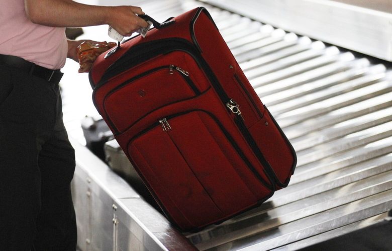 A traveler collects his bag from a luggage carousel at an airport. (AP Photo/Matt Rourke, file)