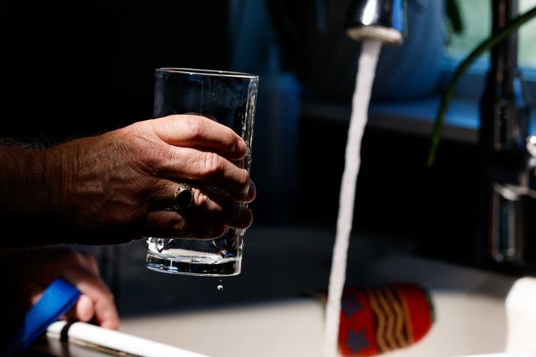 Lance Ostrom fills a glass of water from the tap in his Yakima kitchen. Ostrom’s well, like others in the neighborhood, is contaminated with PFAS chemicals, and he now has a filtration system that cost him more than $7,000. (Jennifer Buchanan / The Seattle Times)