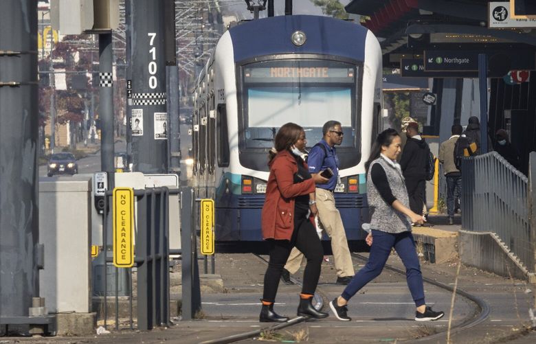 A pedestrian crosses S. Othello St. just south of the Othello light rail station on Martin Luther King Jr. Way S. in Seattle in front of a train that is loading passengers Tuesday, October 18, 2022.  

Sound Transit is turning up the noise to 90 decibels, as a relatively cheap and easy start to safety measures. The goal is to alert people, especially those walking, when trains approach. About one driver or person is hit per month on average.

 221889