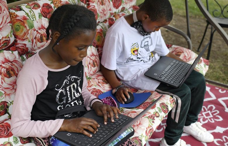 FILE – Fourth-grader Sammiayah Thompson, left, and her brother third-grader Nehemiah Thompson work outside in their yard on laptops provided by their school system for distant learning, in Hartford, Conn., on June 5, 2020. In interviews with The Associated Press, close to 50 school leaders, teachers, parents and health officials reflected on decisions to keep students in extended online learning, especially during the spring semester of 2021. (AP Photo/Jessica Hill) NY514 NY514