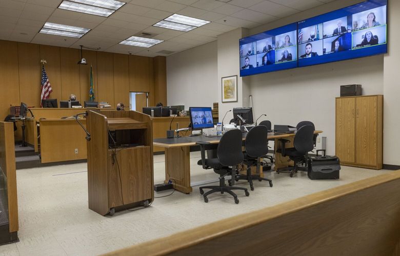 King County Superior Court Judge Melinda J. Young (on bench at top left) watches a computer screen where lawyers appear in a zoom call Friday, October 21, 2022.  (The screen can be seen at top right and on the desk in the foreground).  They are discussing the case of defendants Emily Schacklman and the City of Seattle who are seeking to be dismissed from a lawsuit filed by women who alleged they were trafficked by Solomon “Raz” Simone. They claim the city and the Seattle Police Department were negligent in investigating their complaints, causing more women to be allegedly abused by Simone.
 221931