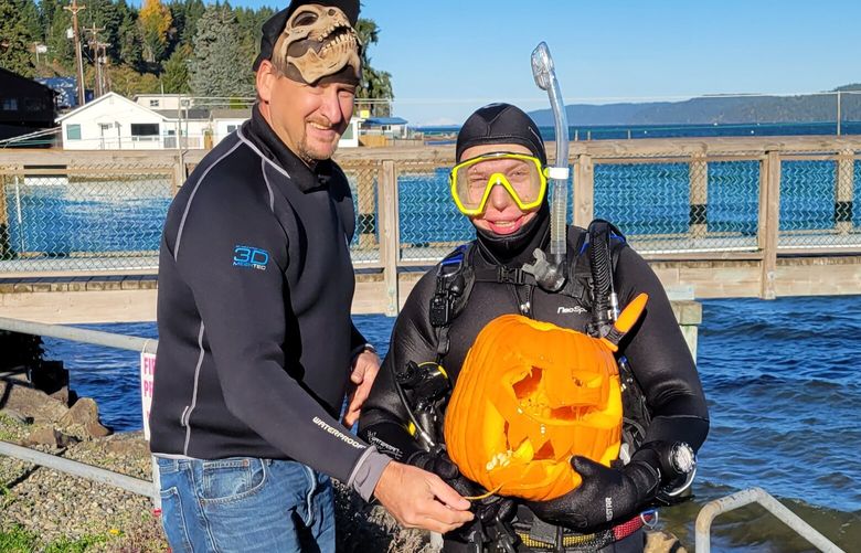 Coordinator John Yackel poses with contestant Tyler Zehfus and his jack-o’-lantern during Yackel Scuba Services’ 2021 underwater pumpkin carving competition at the Port of Hoodsport, in Mason County on the Hood Canal. (Courtesy of Yackel Scuba Services)