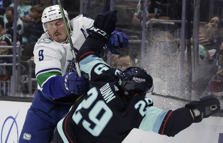 Vancouver Canucks center J.T. Miller (9) colides with Seattle Kraken defenseman Vince Dunn (29) behind the net during the first period of an NHL hockey game, Thursday, Oct. 27, 2022, in Seattle. (AP Photo/John Froschauer) WAJF102 WAJF102