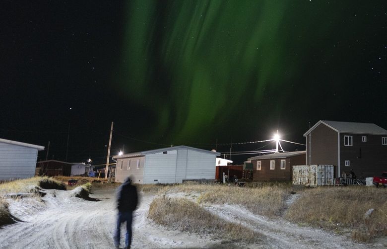 The northern lights appear over Shishmaref, Alaska, Sunday, Oct. 2, 2022. Rising sea levels, flooding, increased erosion and loss of protective sea ice and land have led residents of this island community to vote twice to relocate. But more than six years after the last vote, Shishmaref remains in the same place because the relocation is too costly. (AP Photo/Jae C. Hong) AKJH333 AKJH333