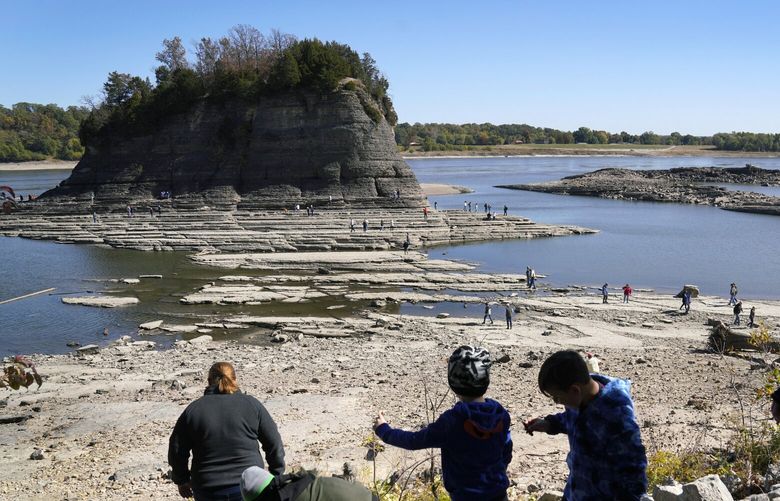 FILE – People walk toward Tower Rock to check out the attraction normally surrounded by the Mississippi River and only accessible by boat, Oct. 19, 2022, in Perry County, Mo. Foot traffic to the rock formation has been made possible because of near record low water levels along the river. (AP Photo/Jeff Roberson, File) CLI101 CLI101
