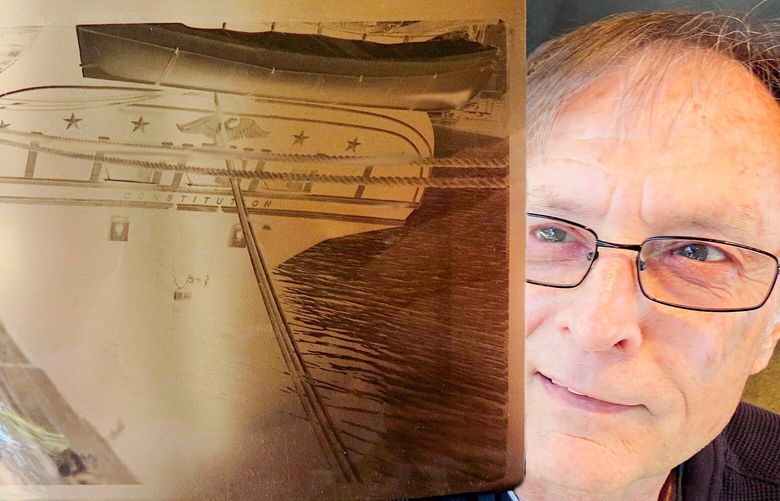 John Gerhard examines one of the 12 negatives he acquired last summer at a West Seattle yard sale. This one shows the stern of the USS Constitution, which bears its name.