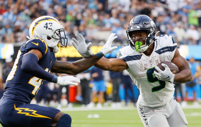 Seattle Seahawks running back Kenneth Walker III goes for the stiff arm on Los Angeles Chargers cornerback Michael Davis during the third quarter. Walker had 168 yards and two touchdowns. (Jennifer Buchanan / The Seattle Times)