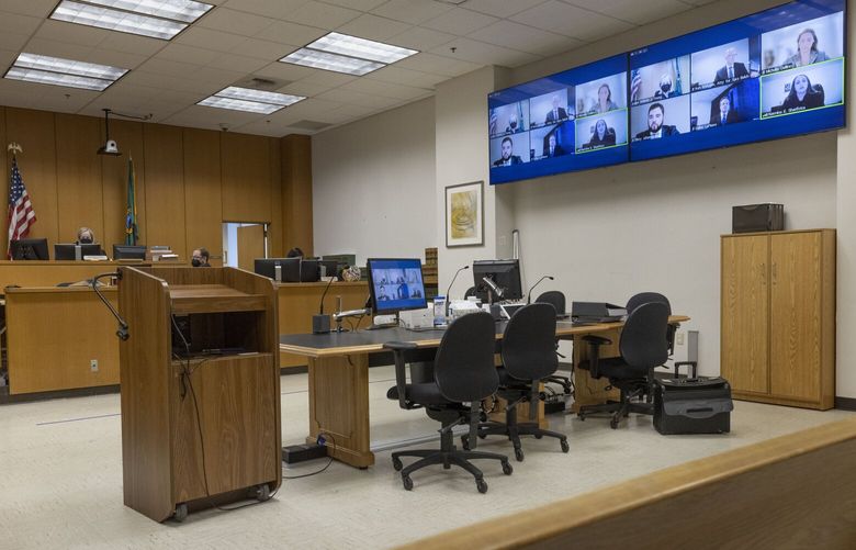 King County Superior Court Judge Melinda J. Young (on bench at top left) watches a computer screen where lawyers appear in a zoom call Friday, October 21, 2022.  (The screen can be seen at top right and on the desk in the foreground).  They are discussing the case of defendants Emily Schacklman and the City of Seattle who are seeking to be dismissed from a lawsuit filed by women who alleged they were trafficked by Solomon “Raz” Simone. They claim the city and the Seattle Police Department were negligent in investigating their complaints, causing more women to be allegedly abused by Simone.
 221931