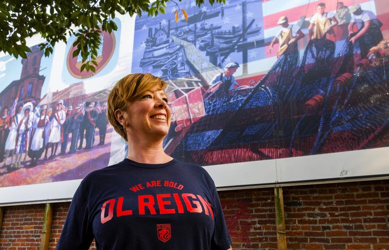 Jen Barnes, the owner of Rough & Tumble, is pictured in the Historic Ballard District, Wednesday, Sept. 14, 2022 in Seattle. Barnes will soon open a bar highlighting womenís sports. In the background is ìThe Mural at Bergen Place,î which celebrates Ballardís Nordic heritage. 221572