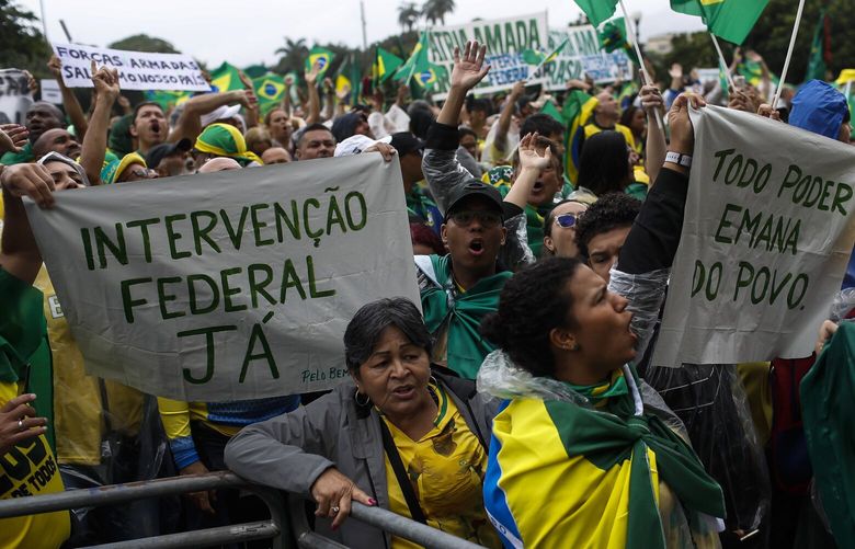 Supporters of President Jair Bolsonaro hold signs with messages that read in Portuguese: “Military intervention now”, left, and “All power emanates from the people”, protest against his defeat in the presidential runoff election, in Rio de Janeiro, Brazil, Wednesday, Nov. 2, 2022. Thousands of supporters called on the military Wednesday to keep the far-right leader in power, even as his administration signaled a willingness to hand over the reins to his rival Luiz Inacio Lula da Silva. (AP Photo/Bruna Prado) XBP107 XBP107