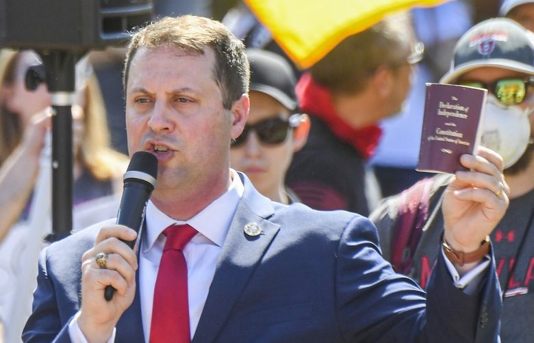 Cox holds up a copy of the Declaration of Independence as he addresses a group seeking to lift coronavirus restrictions amid the pandemic. MUST CREDIT: Washington Post photo by Jonathan Newton.