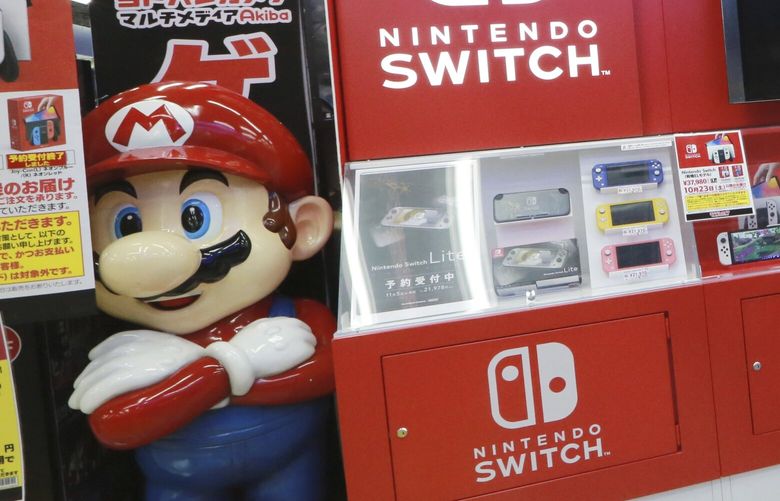A man walks an advertisement of Nintendo Switch at an electronics retail chain store in Tokyo on Oct. 13, 2021. Japanese video game maker Nintendo recorded a 34% surge in fiscal first half profits Tuesday, Nov. 8, 2022, as products for its Switch console like “Splatoon 3,” a paint-shooting game, sold well. (AP Photo/Koji Sasahara) TKMY104 TKMY104