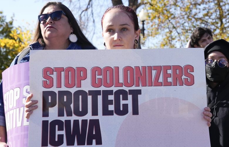 Demonstrators stand outside of the U.S. Supreme Court, as the court hears arguments over the Indian Child Welfare Act, Wednesday, Nov. 9, 2022, in Washington. The Supreme Court is wrestling with a challenge to a federal law that gives preference to Native American families in foster care and adoption proceedings of Native children. (AP Photo/Mariam Zuhaib) DCMZ305 DCMZ305
