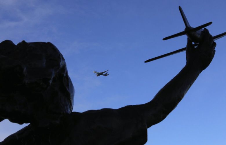 A Prime Air flight bound for Sea-Tac Airport passes by a statue of a girl with a model airplane outside the Museum of Flight, Sunday, Dec. 29, 2019 in Seattle. 212530
