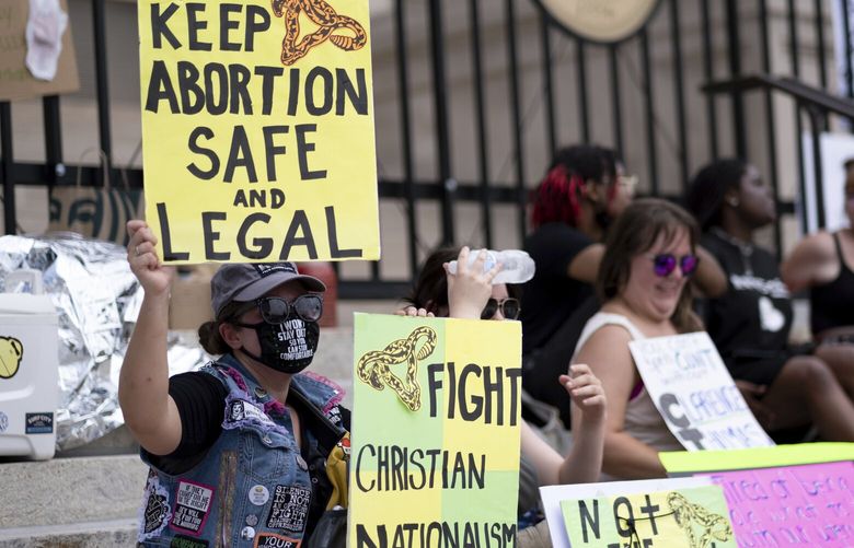 FILE – A small group, including Stephanie Batchelor, left, sits on the steps of the Georgia state Capitol protesting the overturning of Roe v. Wade on June 26, 2022. A judge overturned Georgiaâ€™s ban on abortion starting around six weeks into a pregnancy, ruling Tuesday, Nov. 15, 2022 that it violated the U.S. Constitution and U.S. Supreme Court precedent when it was enacted. (AP Photo/Ben Gray, File) NYSS203 NYSS203