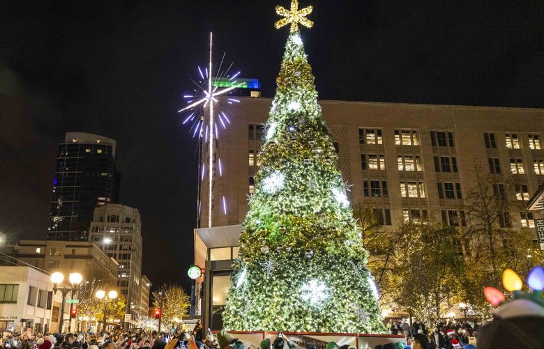 Spectators record on their phones as the Westlake Center tree is lit in Seattle on Black Friday, Nov. 26, 2021.
