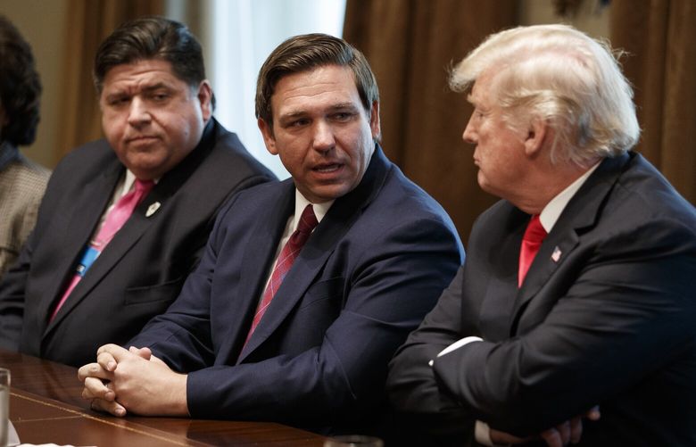 FILE – Governor-elect Ron DeSantis, R-Fla., talks with President Donald Trump during a meeting with newly elected governors in the Cabinet Room of the White House, Dec. 13, 2018, in Washington. From left, Governor-elect J.B. Pritzker, D-Ill., DeSantis, and Trump. (AP Photo/Evan Vucci, File) WX109 WX109
