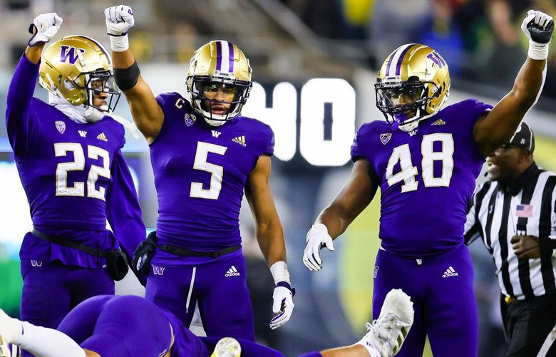 Washington Huskies cornerback Jaivion Green (22), safety Alex Cook (5) and linebacker Edefuan Ulofoshio celebrate after stoping the Ducks on third down late in the fourth quarter. The Ducks would go for it on fourth and turn the ball over on downs.  222148 222148