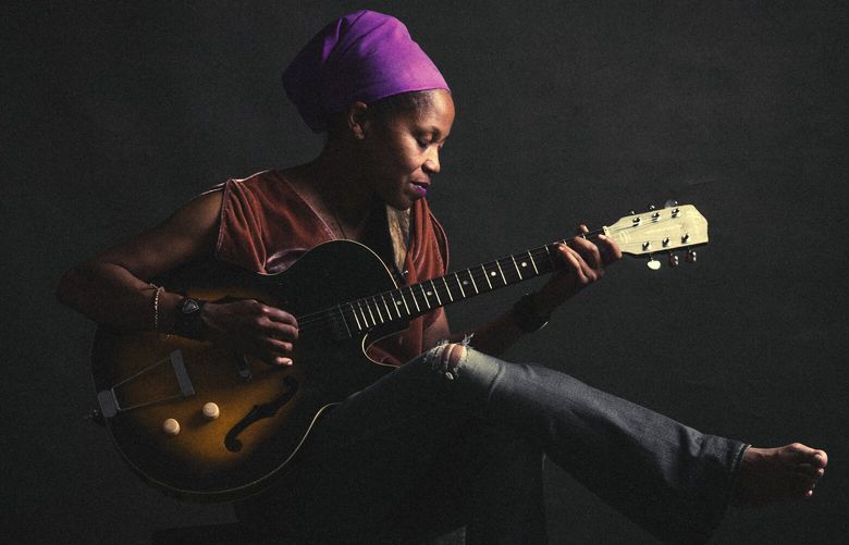 JR Rhodes, a Seattle-based singer-songwriter, sits with her guitar for a photo in 2021.