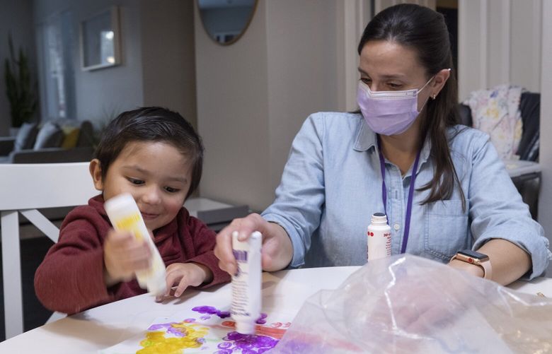 Kindering speech and language pathologist Kaitlyn McClain (r) helps almost three-year-old Steve, who has been slow to speak, with his art project in the family’s Issaquah home Tuesday, November 15, 2022. Steve also has behavioral issues, which another therapist is working on in different sessions. 222155