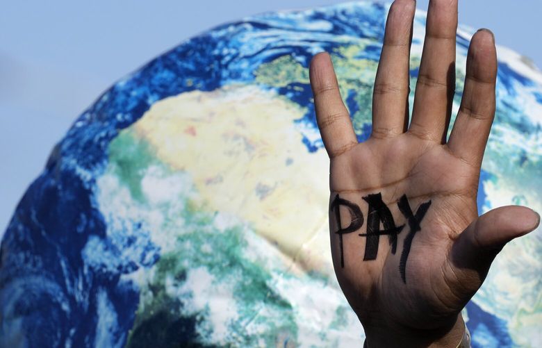 A hand reads “pay” calling for reparations for loss and damage at the COP27 U.N. Climate Summit, Friday, Nov. 18, 2022, in Sharm el-Sheikh, Egypt. (AP Photo/Peter Dejong) CLI157 CLI157