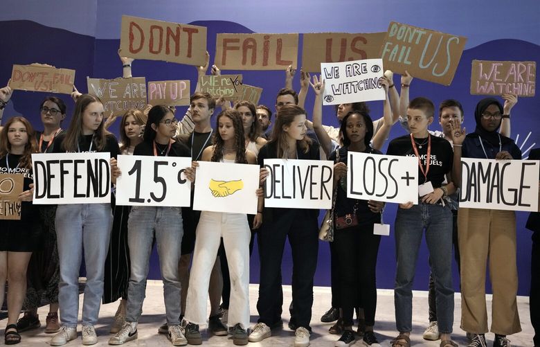 Youth activists hold signs encouraging world leaders to maintain policies that limit warming to 1.5 degrees Celsius since pre-industrial times and provide reparations for loss and damage at the COP27 U.N. Climate Summit, Saturday, Nov. 19, 2022, in Sharm el-Sheikh, Egypt. (AP Photo/Nariman El-Mofty) CLI163 CLI163