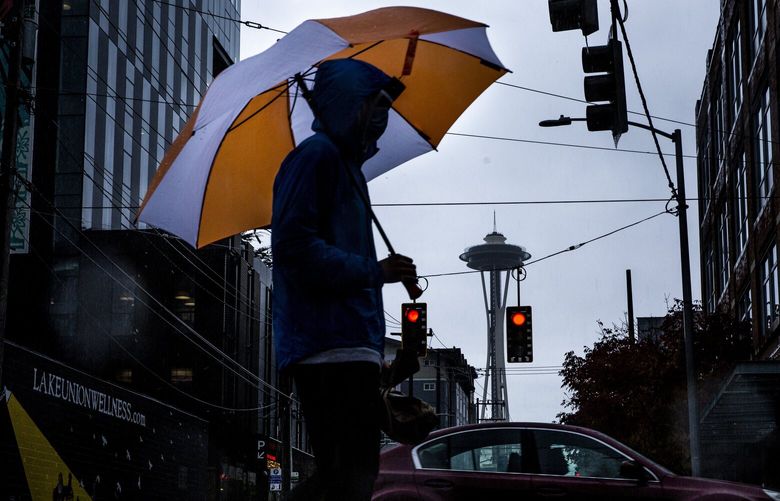 A man holds an umbrella as he walks across the street in South Lake Union in Seattle on a rainy Monday, Sept. 27, 2021. LO 218351
