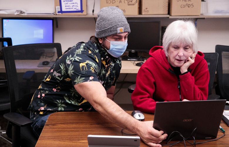 Joyce Hengesbach, right, works with volunteer Vance Richmond during a session at the Senior Center of West Seattle where seniors bring in their electronic devices and are taught how to use them Thursday, November 17, 2022. 222185