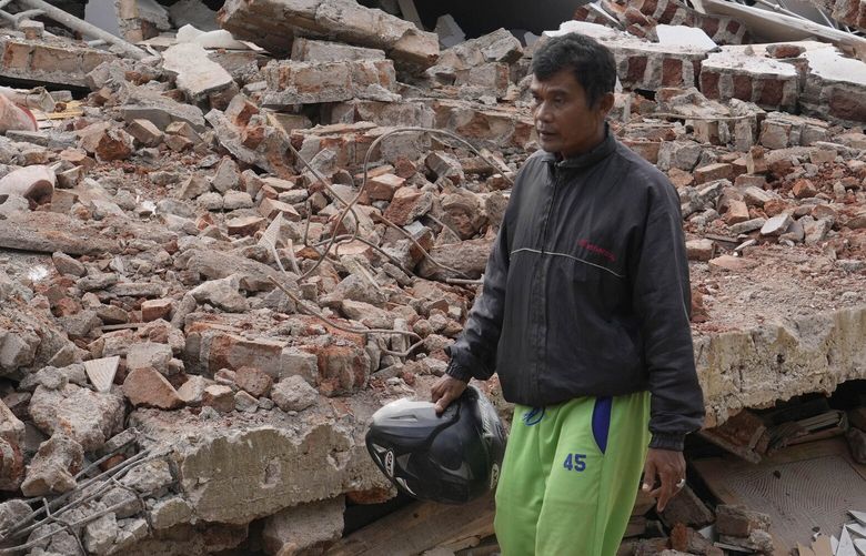 Enjot, center, who like many Indonesians only use one name, walks along the ruins of a building flattened to the ground during Monday’s earthquake in Cianjur, West Java, Indonesia, Tuesday, Nov. 22, 2022. Enjot was out tending to his cows when the earth started to shake around him. Before he could even comprehend what was going on, his daughter was on the phone to tell him the earthquake had brought down his house. By Tuesday, he would learn that 11 of his relatives were among those killed in the earthquake, whose epicenter was only a few kilometers (miles) south of his village.Â (AP Photo/Tatan Syuflana) XJAK138 XJAK138