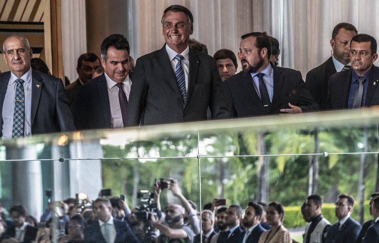 FILE – President Jair Bolsonaro smiles at reporters, reflected in mirrored decor, as he arrives at a news conference in Brasilia, Brazil, Nov. 1, 2022. This week, President Jair Bolsonaro’s campaign filed a request to effectively overturn the election he lost, saying the discovery of a software bug, which Independent experts say had no impact on the integrity of the vote, should nullify votes from about 60 percent of the voting machines. (Dado Galdieri/The New York Times) XNYT212 XNYT212