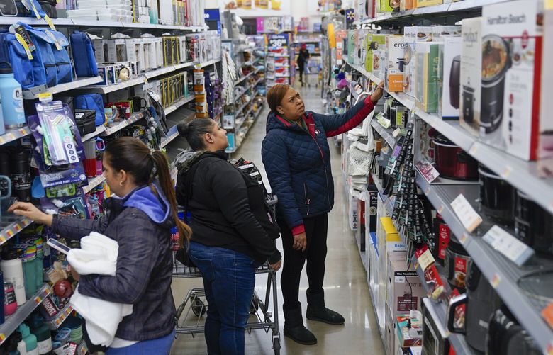 Chris Velez, center, and Laketha Champion, right, shop for a co-workers at a Walmart in Secaucus, N.J., Tuesday, Nov. 22, 2022. (AP Photo/Seth Wenig) 