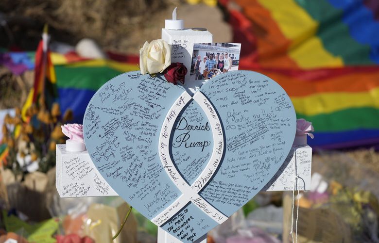 Hand-written messages cover the heart attached to the cross to honor a victim of the mass shooting at a gay nightclub at a makeshift memorial near the scene of the crime Wednesday, Nov. 23, 2022, in Colorado Springs, Colo.  The alleged shooter facing possible hate crime charges in the fatal shooting of five people at a Colorado Springs gay nightclub is scheduled to make their first court appearance Wednesday from jail after being released from the hospital a day earlier.  (AP Photo/David Zalubowski) CODZ111 CODZ111