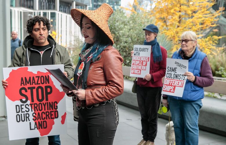 Author and poet Sasha LaPointe, of the Upper Skagit and Nooksack Indian Tribe, center, talks about the Liesbeek Action Campaign and Amazon halting development on its African headquarters in Cape Town outside of Amazon offices in Seattle, Wednesday, Nov. 23, 2022. Puget Sound Sage’s Fernando Mejia Ledesma, at left, delivered a petition with more than 70,000 signatures to Amazon. 222264