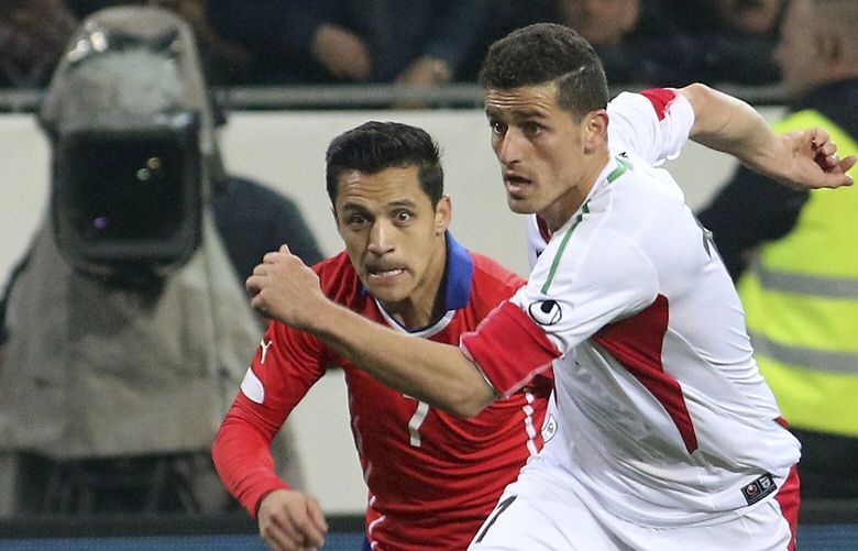 FILE â€”  Voria Ghafouri, right, then an Iranian national team soccer player, challenges for a ball with Chile’s Alexis Alejandro Sanchez during a friendly soccer match in St. Poelten, Austria, March 26, 2015. The semiofficial Fars and Tasnim news agencies reported on Thursday, Nov. 24, 2022, that Iran arrested Ghafouri, a prominent former member of its national soccer team for insulting the national soccer team, which is currently playing in the World Cup, and criticizing the government as authorities grapple with nationwide protests. (AP Photo/Ronald Zak, File) CAITH405 CAITH405