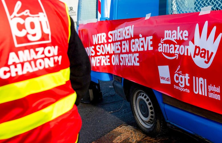 A ‘Make Amazon Pay’ banner on a vehicle at a General Confederation of Labour (CGT) union protest during strike action at the Amazon.com fulfillment center in Bretigny-sur-Orge, France, on Wednesday, Nov. 25, 2022. Amazon employees in the US, UK, India, Japan, Australia, South Africa and across Europe are demanding better wages and working conditions as the cost-of-living crisis deepens, in a campaign dubbed “Make Amazon Pay.” Photographer: Benjamin Girette/Bloomberg 775905399