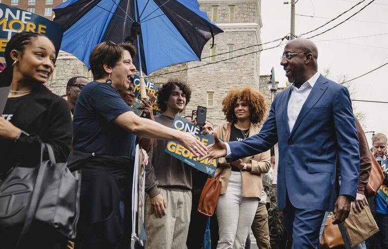 Sen. Raphael Warnock (D-Ga.), center, arrives to speak to a crowd in front of the John Lewis mural as his campaign heads towards a runoff election, in Atlanta, Ga. on Nov. 9, 2022. The runoff election for the Georgia Senate race is scheduled for Dec. 6. (Nicole Craine/The New York Times) XNYT77 XNYT77