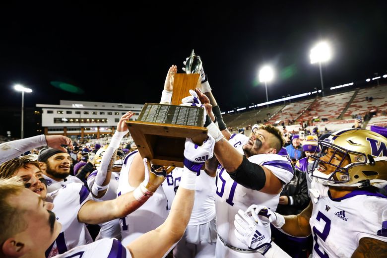 Offensive lineman Jaxson Kirkland and teammates hoist the trophy after the Washington Huskies beat the Washington State Cougars 51-33 in the Apple Cup Saturday, November 26, 2022 at Martin Stadium, in Pullman, WA. (Dean Rutz / The Seattle Times)