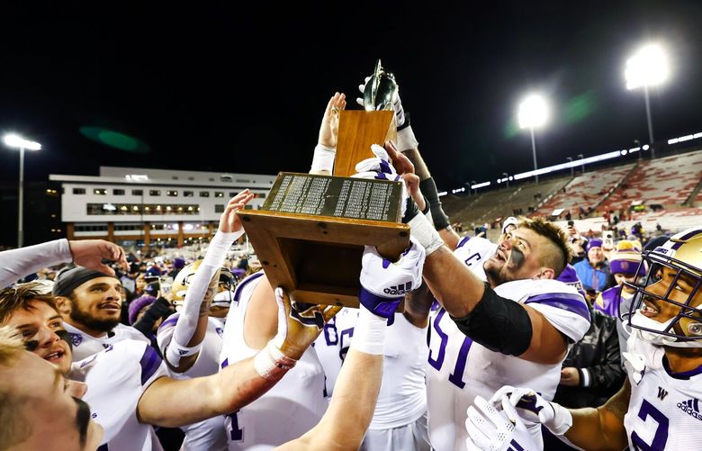 Offensive lineman Jaxson Kirkland and teammates hoist the trophy after the Washington Huskies beat the Washington State Cougars 51-33 in the Apple Cup Saturday, November 26, 2022 at Martin Stadium, in Pullman, WA.  222254